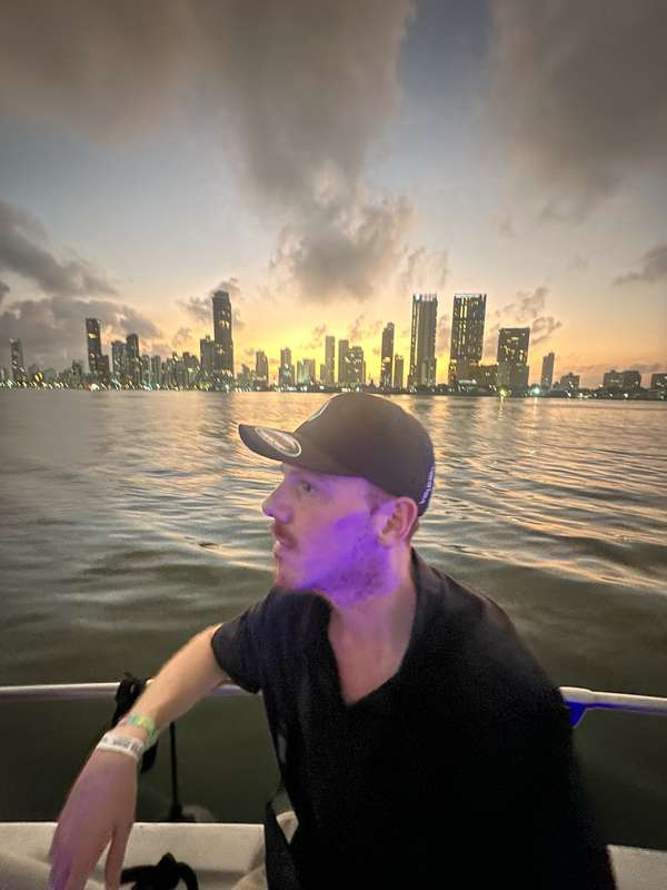 Boot bei Sunset — lila Party-Lichter, Skyline im Hintergrund