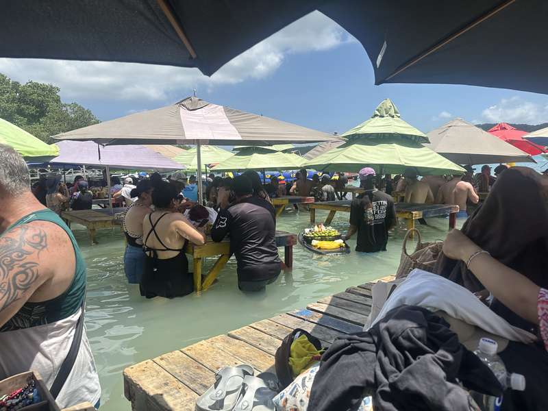 Überfüllte Insel-Bar im Wasser — Tische, Schirme, Menschenmassen