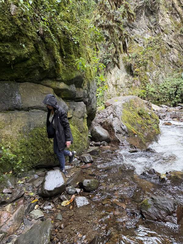 Wanderer navigiert nasse Felsen neben Bach