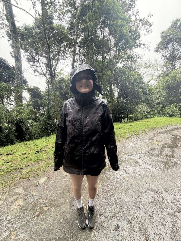 Sarah lächelnd im Regen, durchnässte Regenjacke