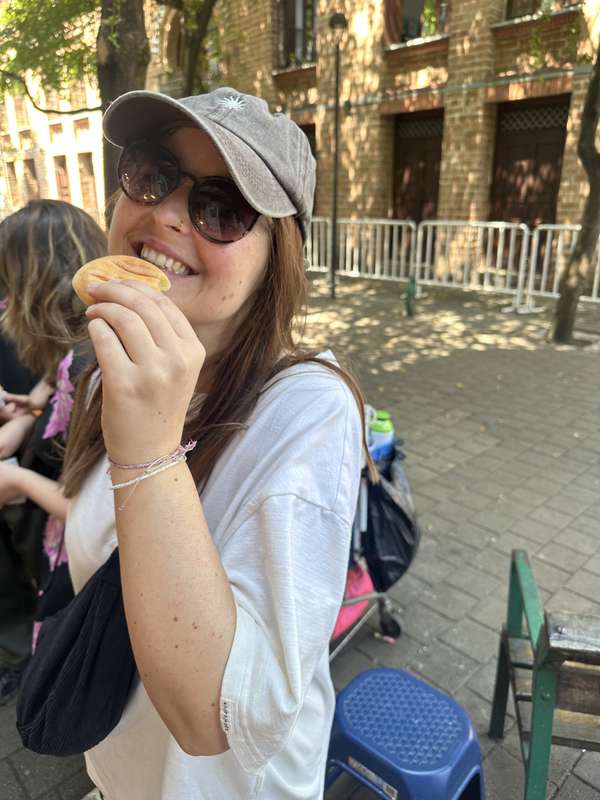 Sarah beißt in Pandebono, lächelnd